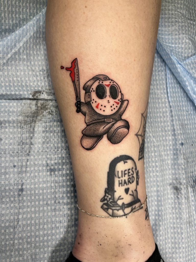 Tattoo of a cartoon character dressed as a horror movie killer holding a blood-dripping axe.