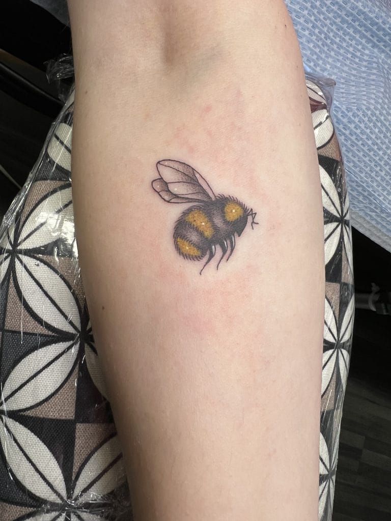 Detailed bee tattoo with black and yellow coloring on a persons arm.