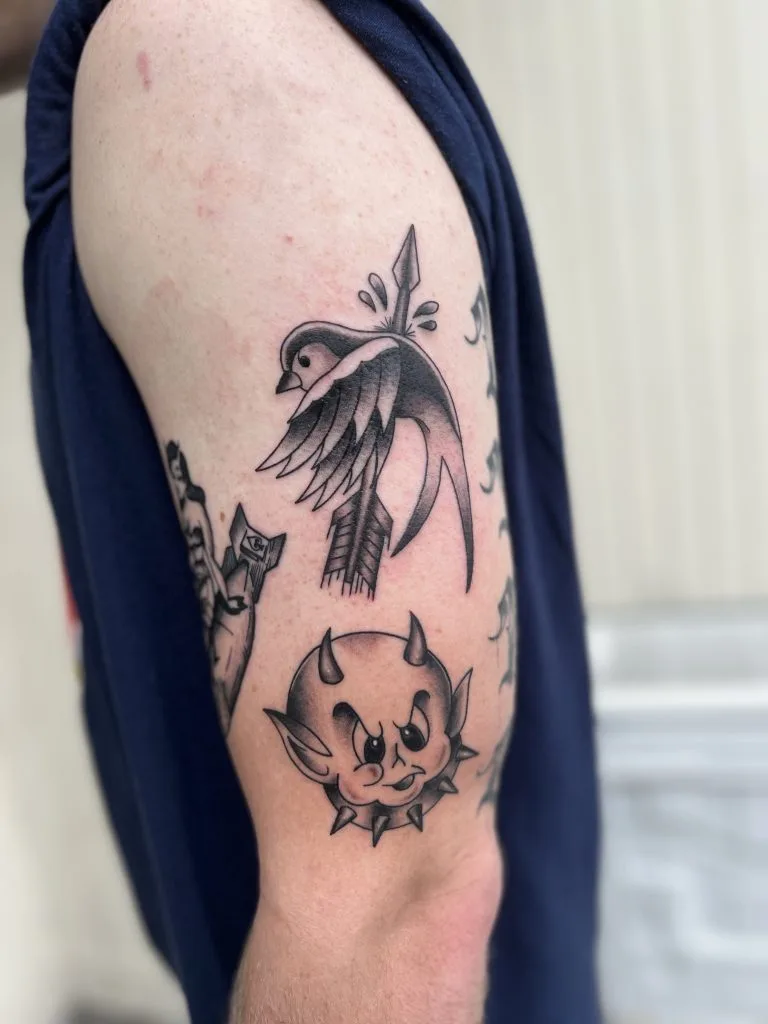 Tattoo of a bird with a sword on its head and a cute, spiky monster face below.