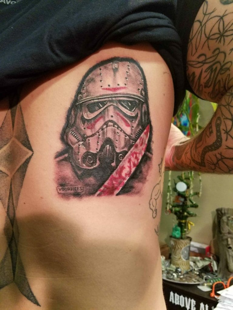 Tattoo of a Stormtrooper helmet with a red lightsaber and the word VOORHEES below.