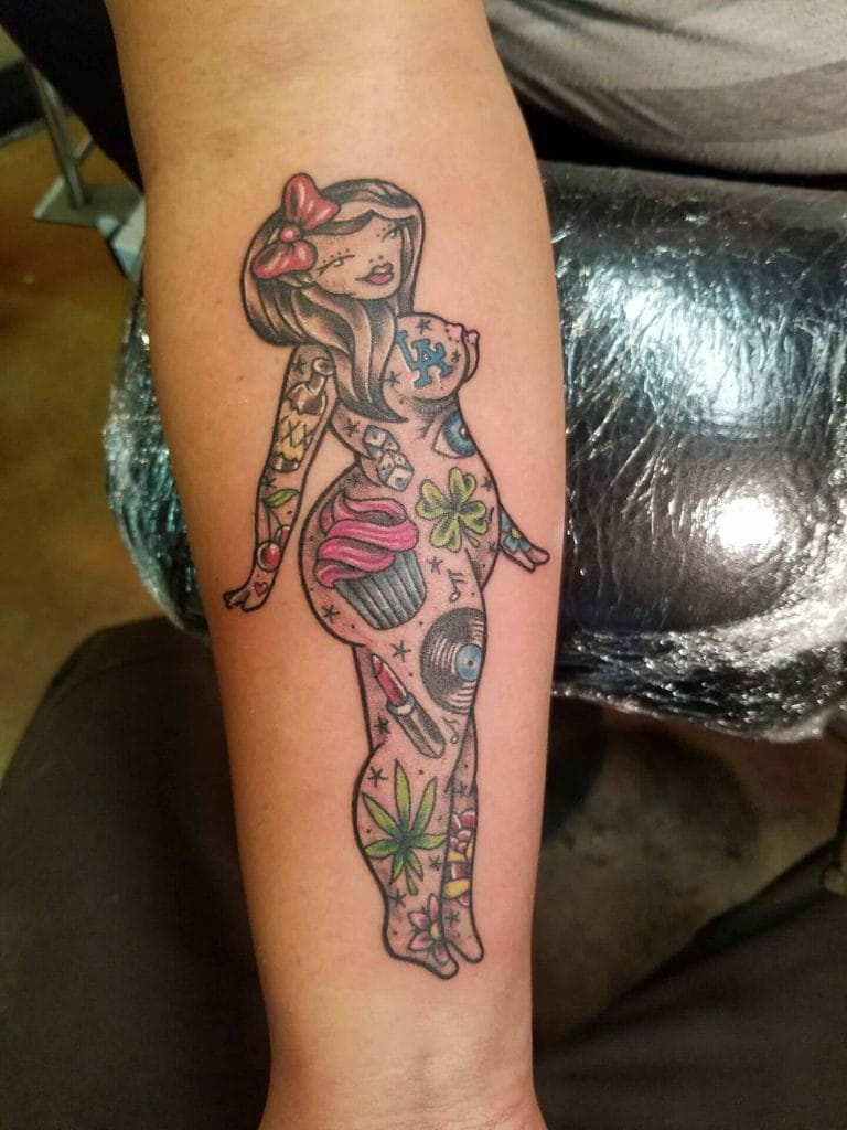 Colorful tattoo of a stylized girl with tattoos, a cupcake, a vinyl record, and cannabis leaves.