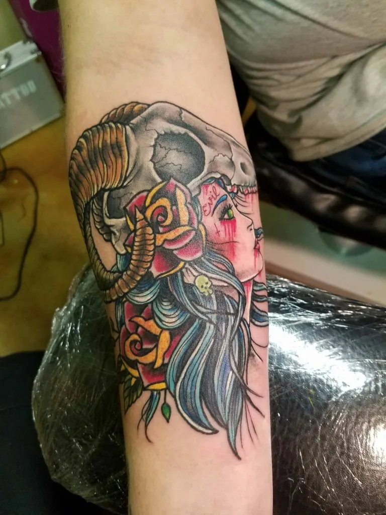 Colorful tattoo of a womans profile with flowing hair, a ram skull, and a tiger face.