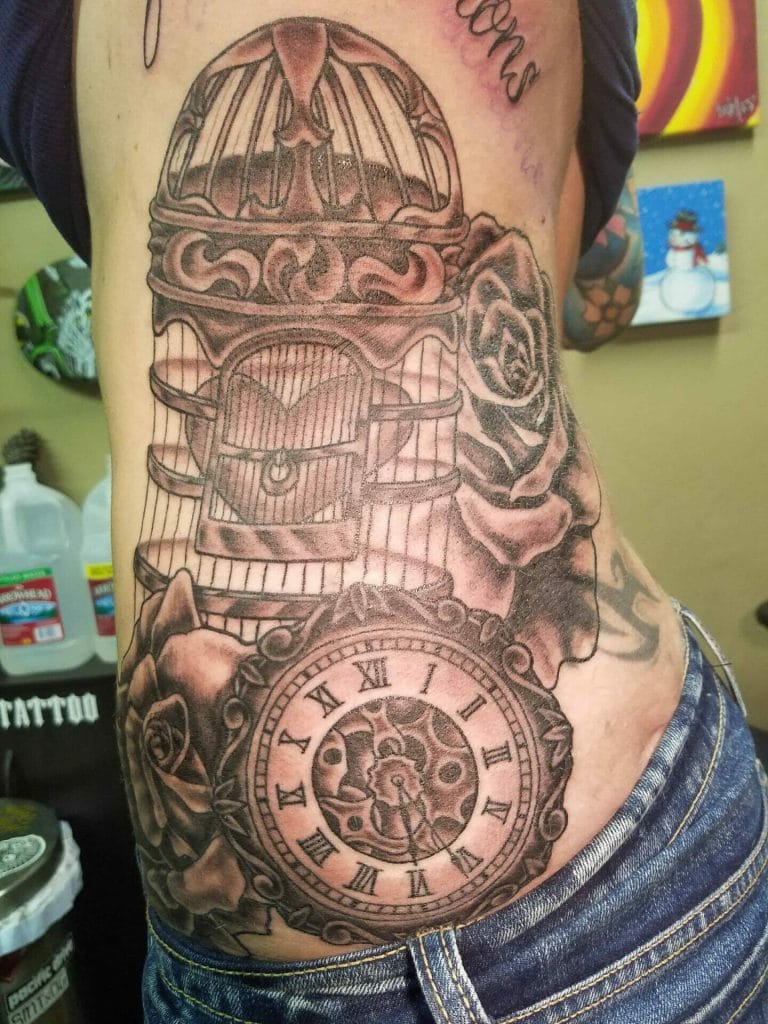 Detailed black and gray tattoo of a vintage pocket watch, roses, a birdcage, and a womans profile.