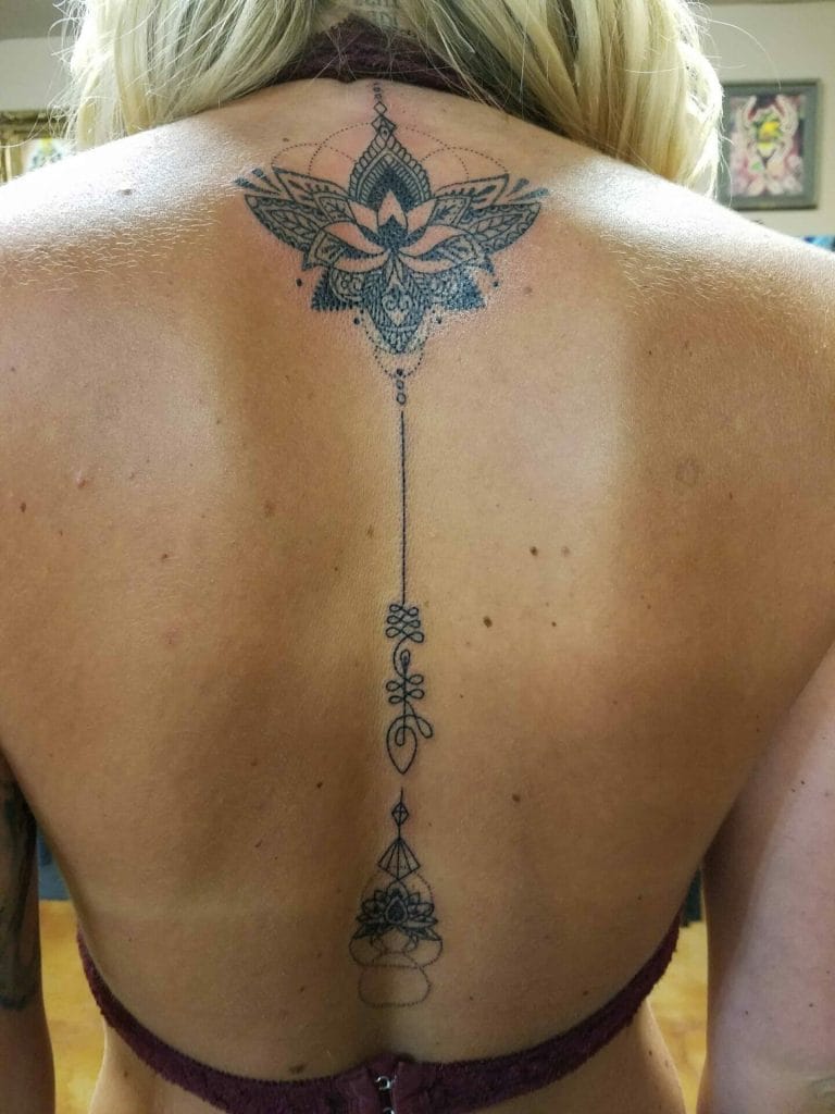 Intricate black line tattoo of a butterfly with geometric and floral details on upper back.