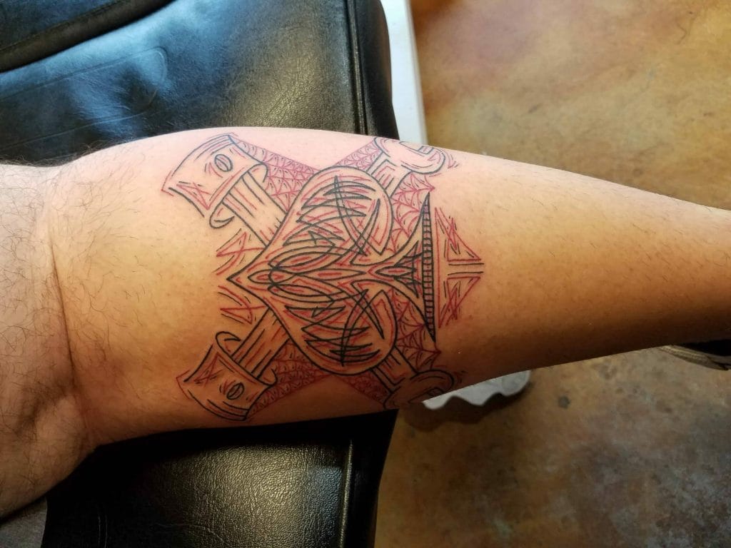 Tattoo of a large, detailed design with swords, geometric patterns, and abstract elements on a persons thigh.