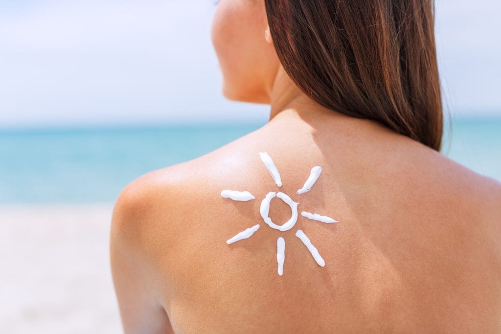 A person at the beach in San Diego, with sunscreen applied in the shape of a sun on their shoulder, showcases perfect skin protection for a coastal climate.
