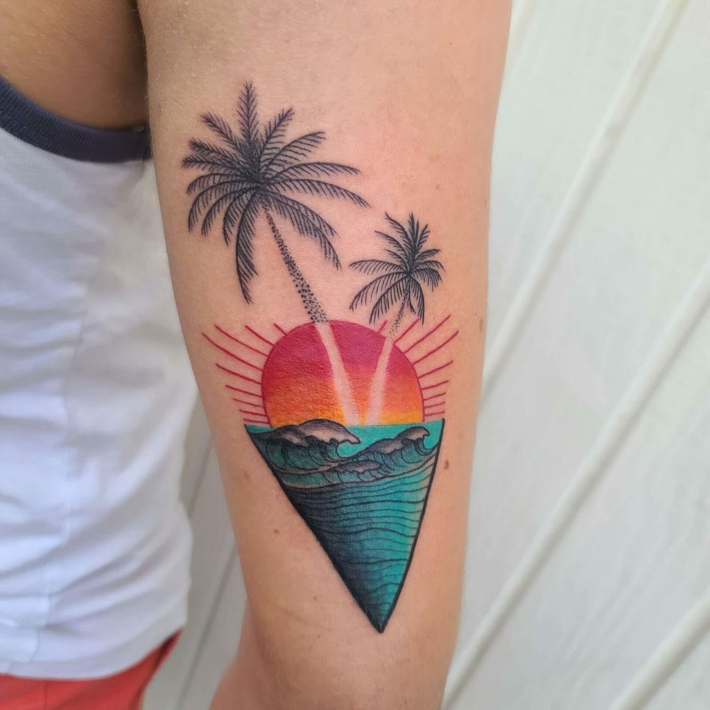 Colorful sunset with ocean waves and two palm trees in a triangular design tattoo.