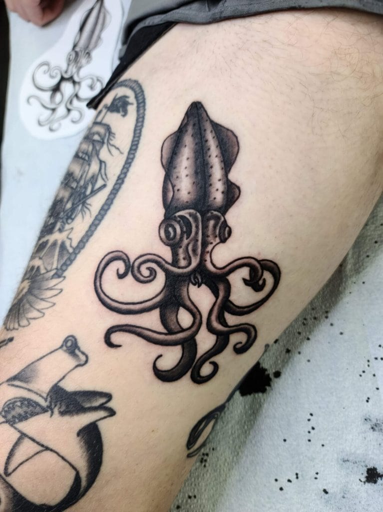 Black and gray octopus tattoo on persons thigh, with detailed tentacles and head.