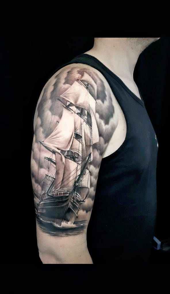 Detailed black and gray sailing ship tattoo on persons upper arm and shoulder.