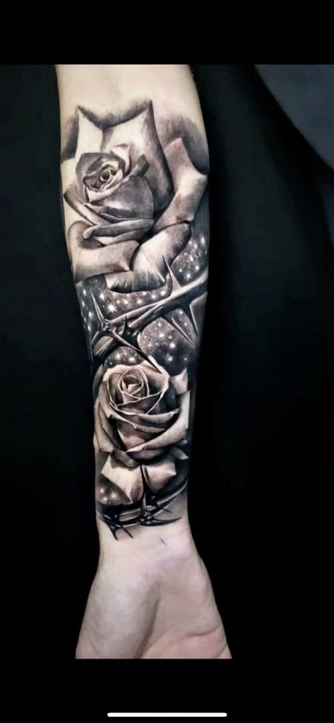 Black and gray tattoo of a hand holding a rose, with stars and thorns below.