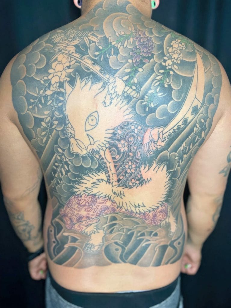 Large colorful dragon tattoo covering the persons back with clouds, flowers, and a sword.