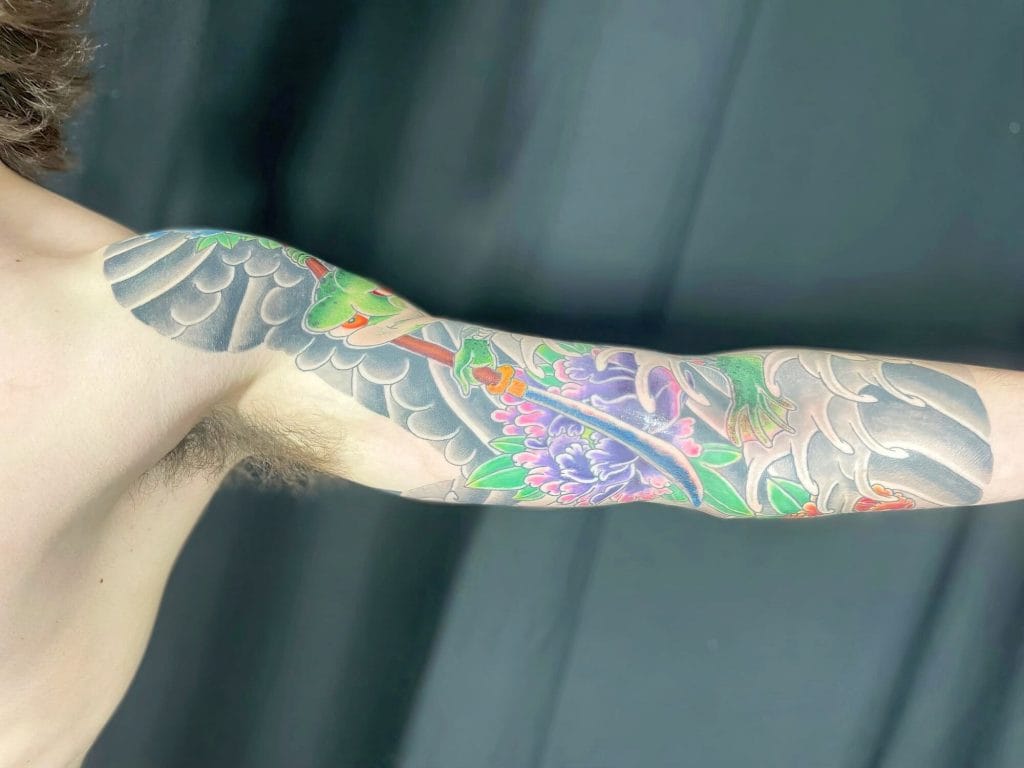 Colorful tattoo sleeve with flowers, leaves, and a dragon extending from shoulder to forearm.