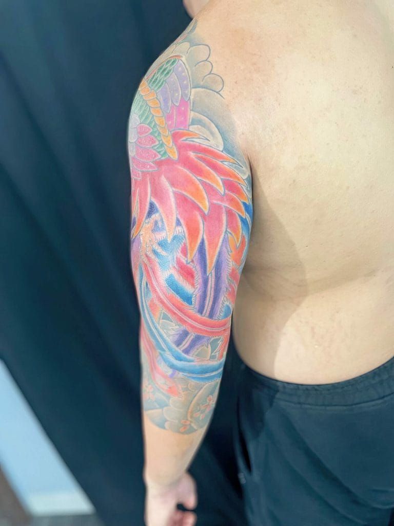 Colorful dragon tattoo covering the upper arm and shoulder of a person.