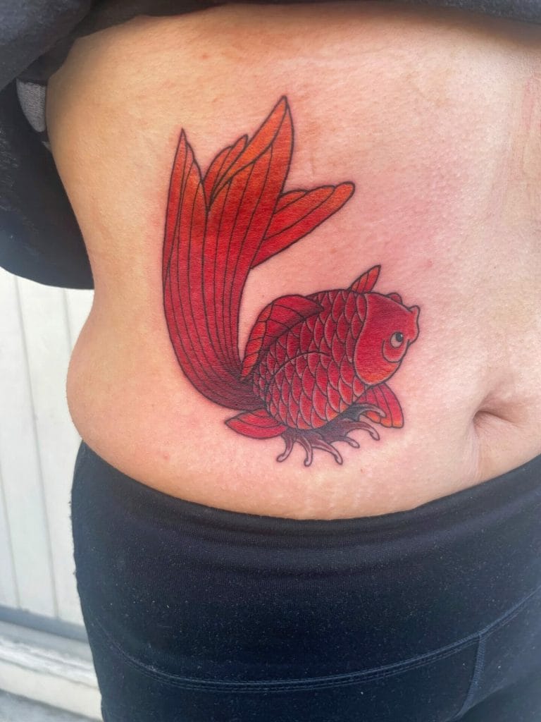 Red fish with large fins and detailed scales tattooed on persons side.