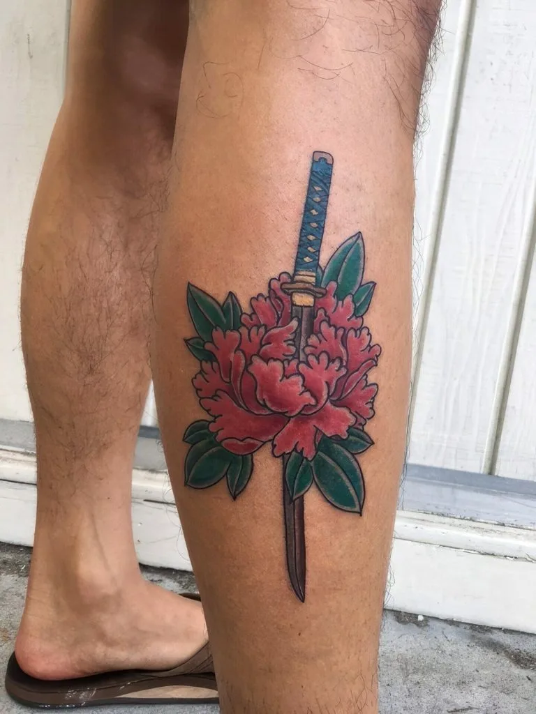 Pink peony flower with green leaves and a blue and gold katana sword piercing through it.