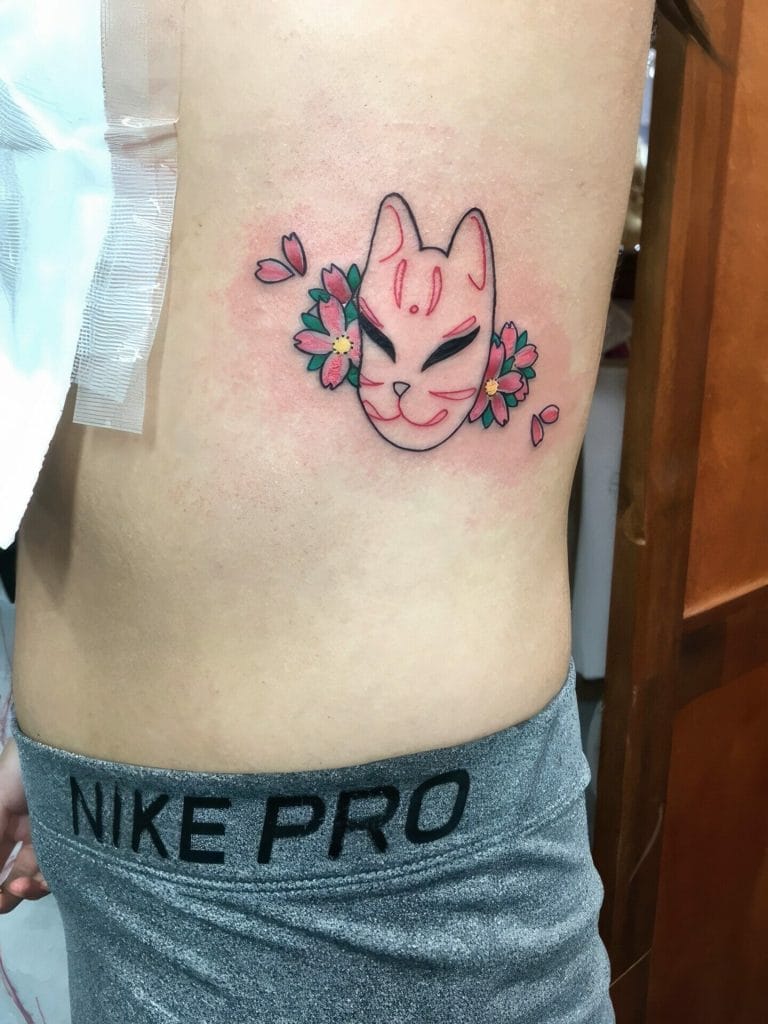 Pink and black outlined lucky cat face with pink flowers and petals around it.