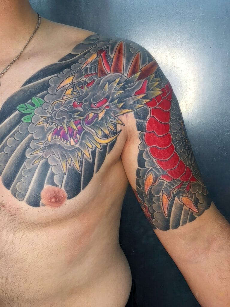 Colorful dragon tattoo with black, red, orange, yellow, and green details on shoulder and chest.