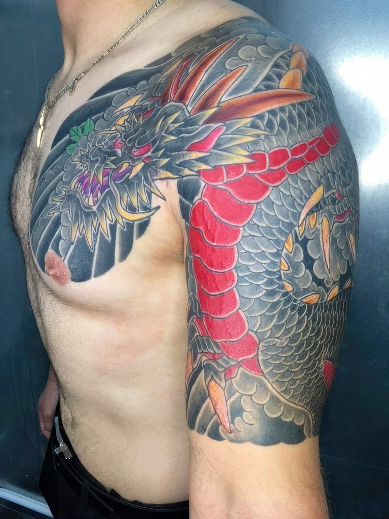 Colorful dragon tattoo with a fierce face, red and black scales, and detailed shading.