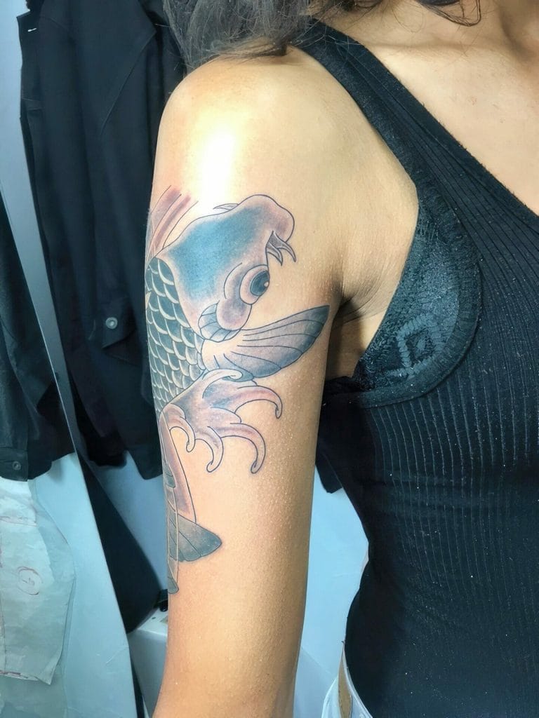 Colorful koi fish tattoo on upper arm with detailed scales and flowing fins.