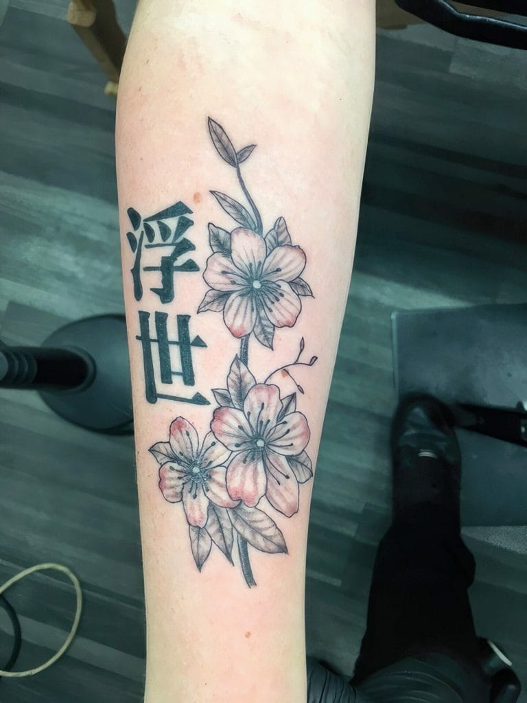 Cherry blossoms with Japanese characters on forearm, black and pink ink.