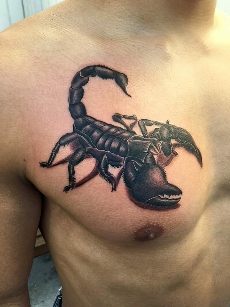 Black and gray scorpion tattoo on persons chest, near the shoulder.