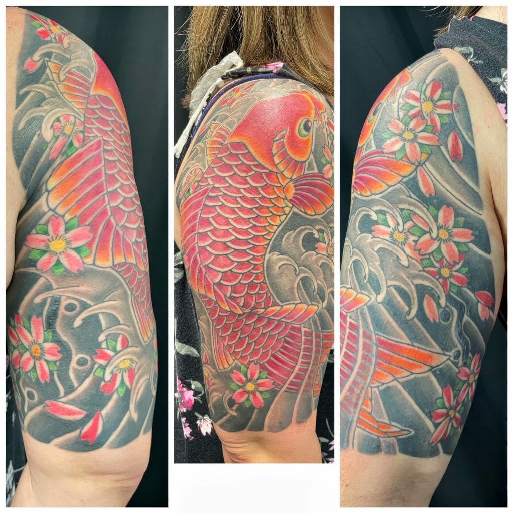 Colorful koi fish and cherry blossom tattoo on persons upper arm.