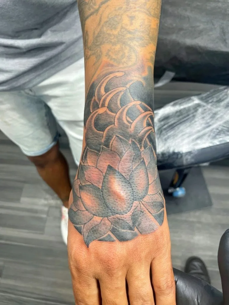 Detailed black and gray tattoo of a succulent plant on the persons forearm.