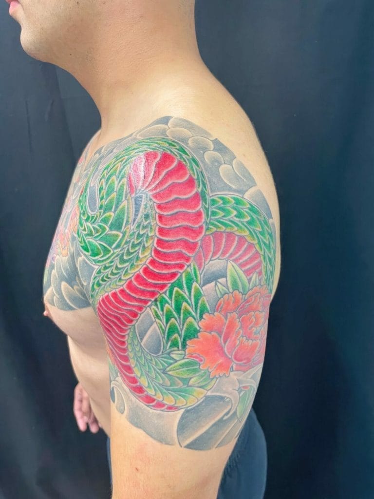 Colorful snake and flower tattoo on persons upper arm and shoulder.
