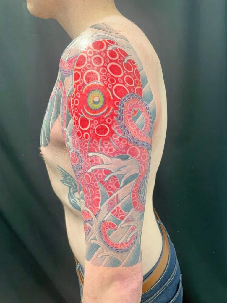 Colorful octopus tattoo with red, purple, and blue hues covering the upper arm and shoulder.