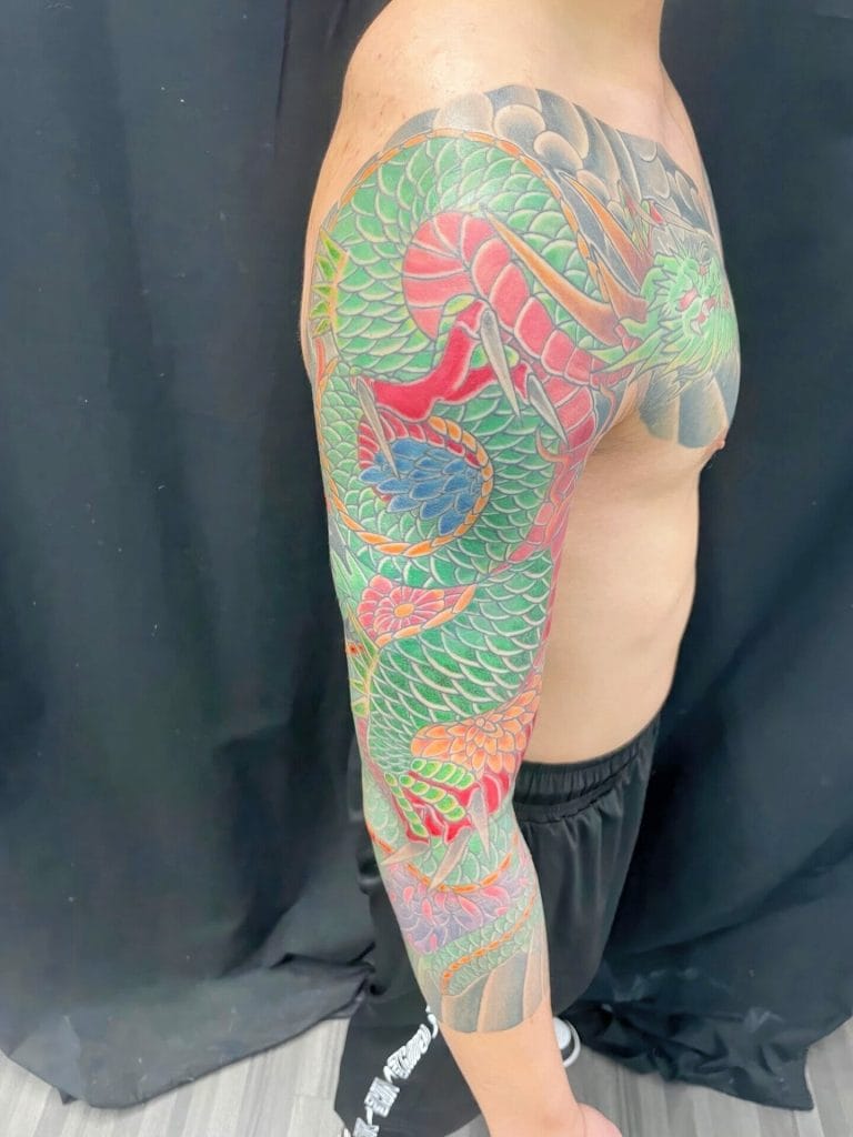 Colorful traditional Japanese dragon tattoo covering the arm and shoulder.