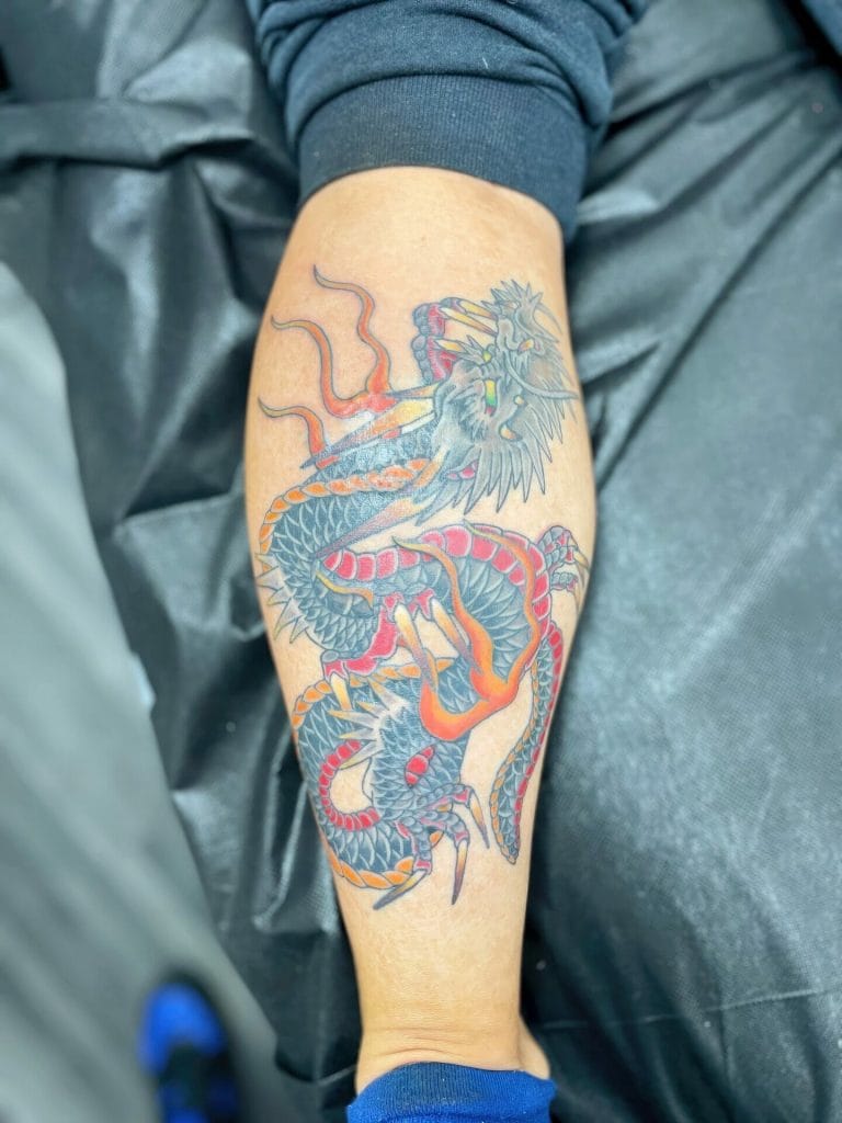 Colorful dragon tattoo with a fierce expression, detailed scales, and fiery accents.