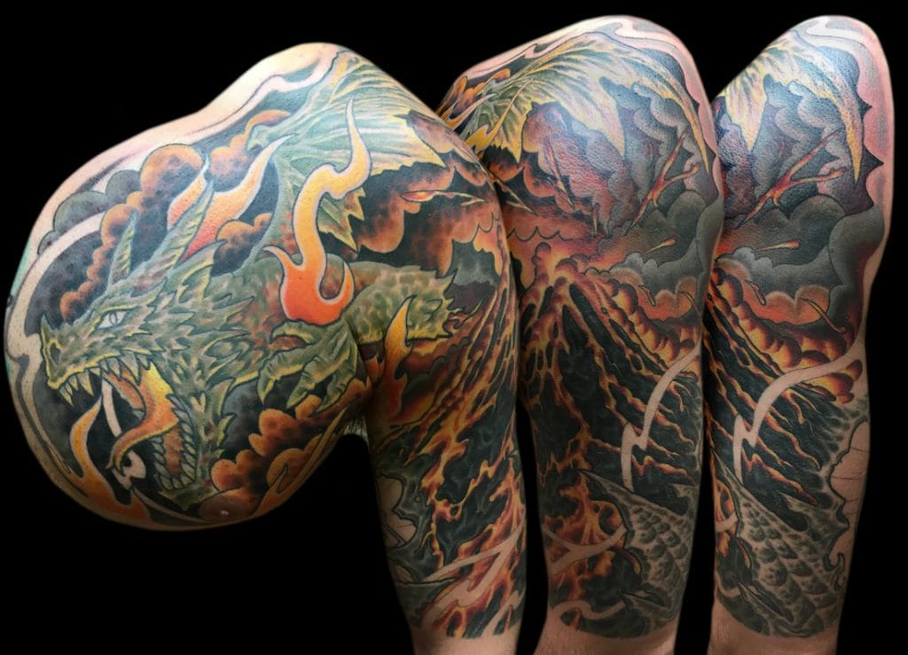 Colorful dragon tattoo covering the shoulder and arm with flames and clouds.