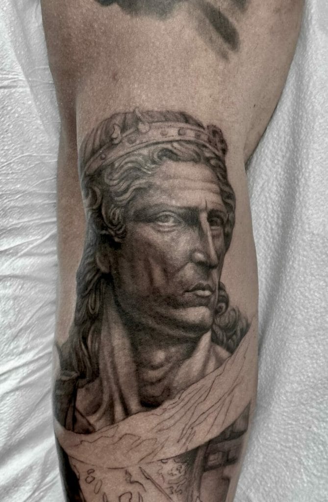 Detailed grayscale tattoo of a regal woman with a crown and flowing hair on a persons leg.