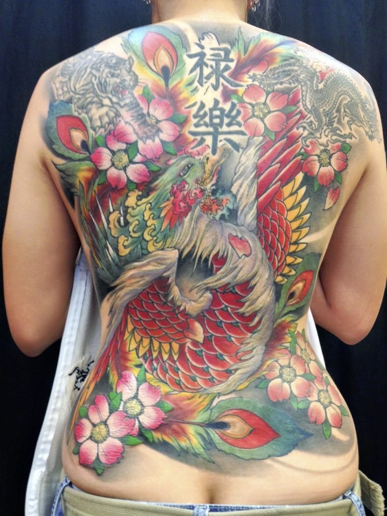Colorful dragon, phoenix, cherry blossoms, and Japanese characters tattoo covering back.