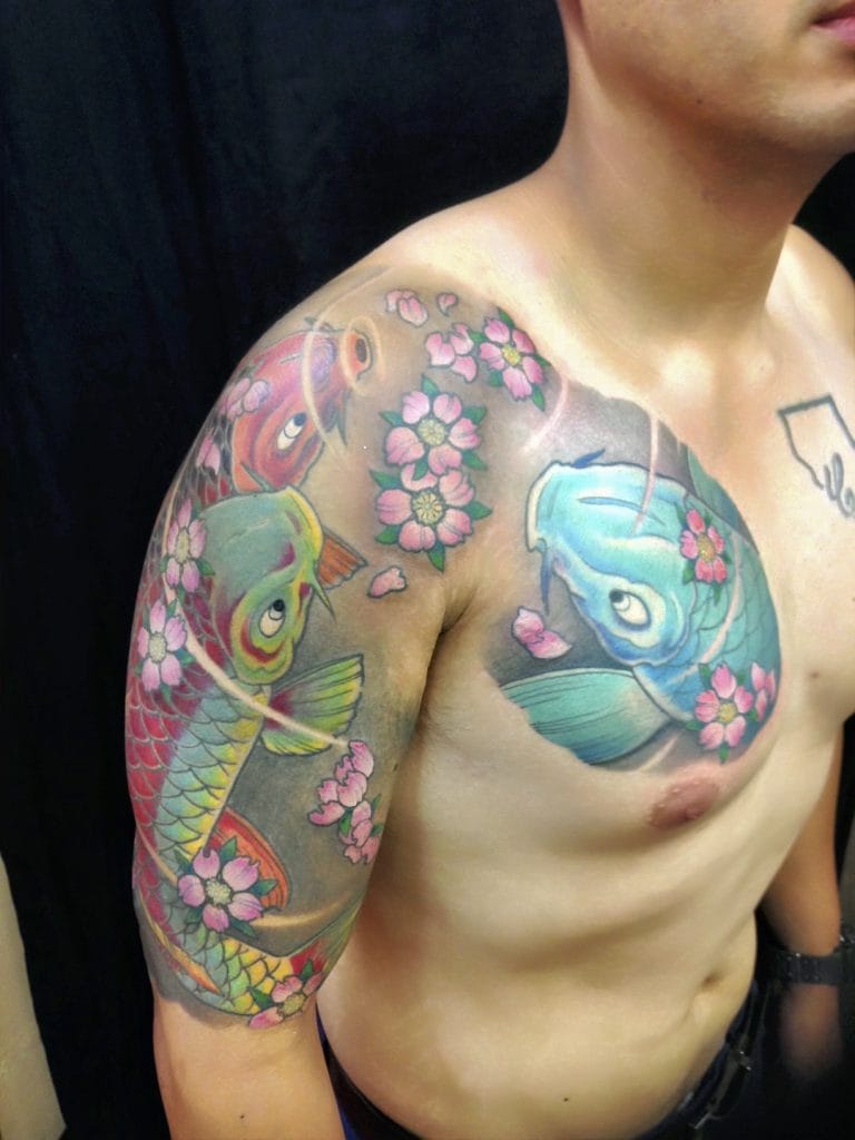 Colorful koi fish and pink cherry blossoms tattoo on mans shoulder and chest.