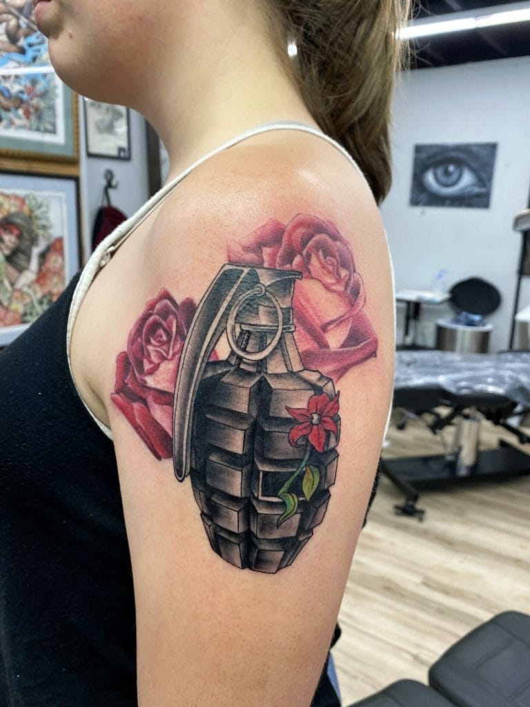 Black and gray hand grenade tattoo with red roses and a red flower on the shoulder.