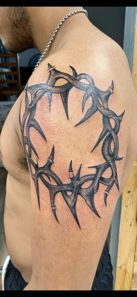 Spiked circular tattoo with sharp, jagged black and gray designs on upper arm.