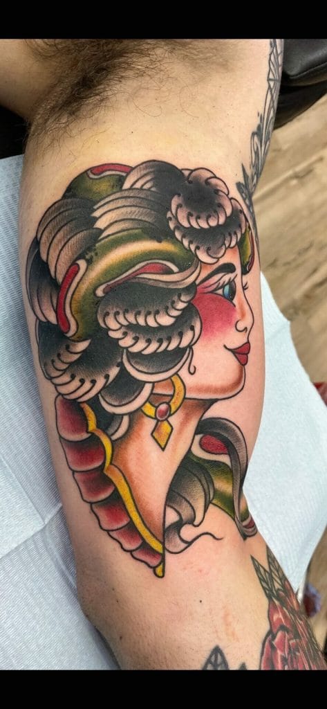 Colorful tattoo of a womans profile with curly hair, jewelry, and decorative elements.
