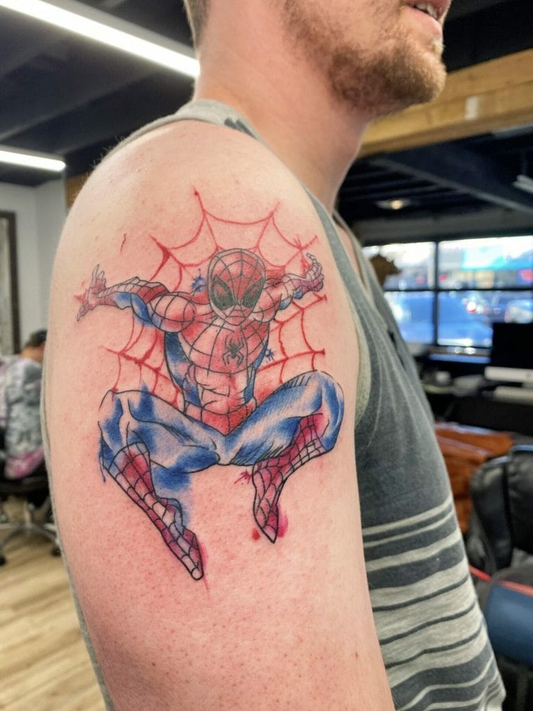 Spider-Man crouching with a web background on mans upper arm tattoo.