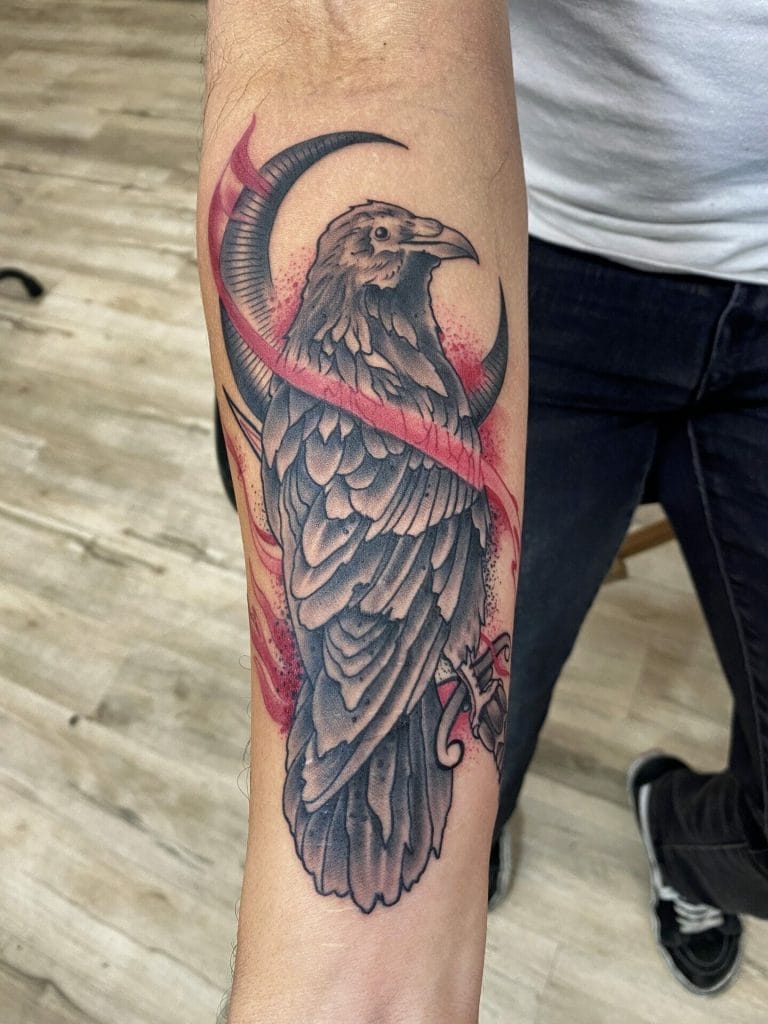 Detailed black and gray eagle with red accents and swirling elements on forearm.
