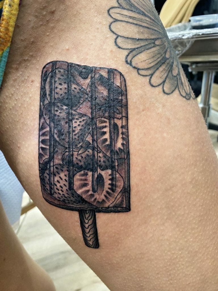 Black and gray tattoo of a popsicle with a woodgrain stick on upper arm.