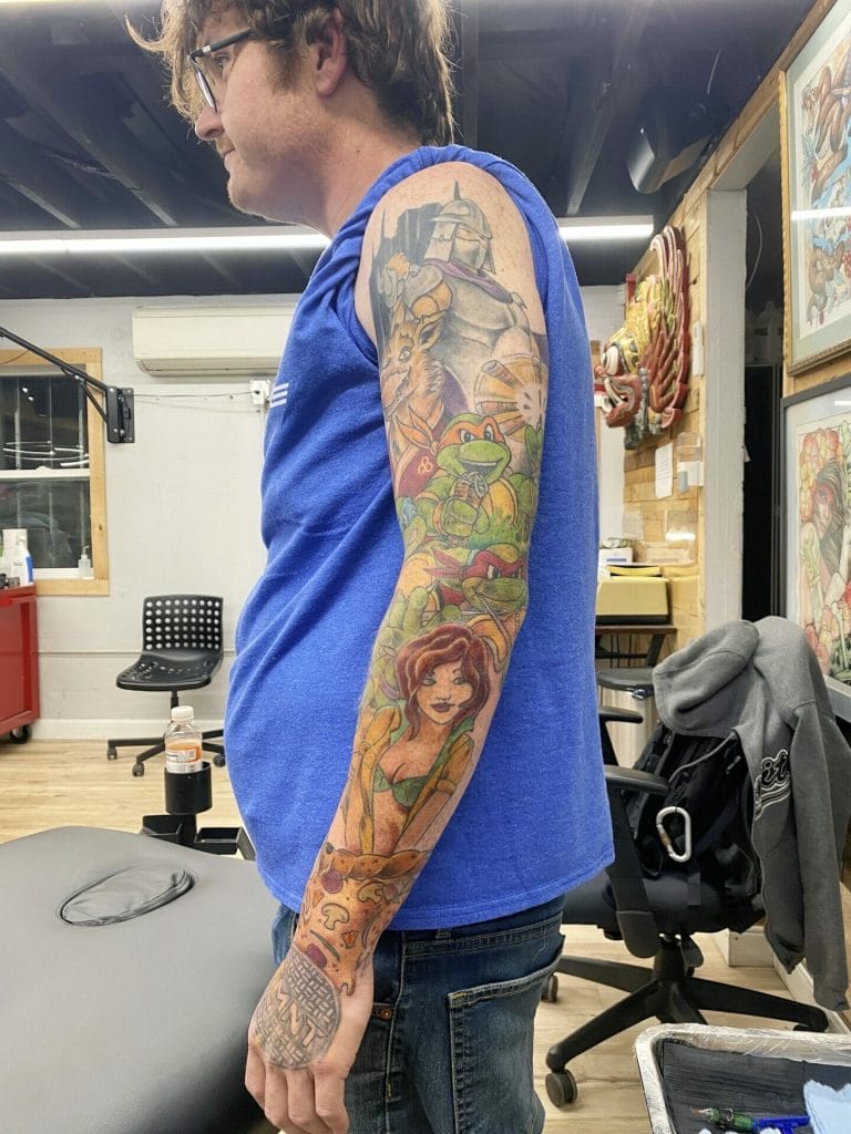 Colorful tattoo sleeve featuring characters from Teenage Mutant Ninja Turtles and Disneys Ariel.