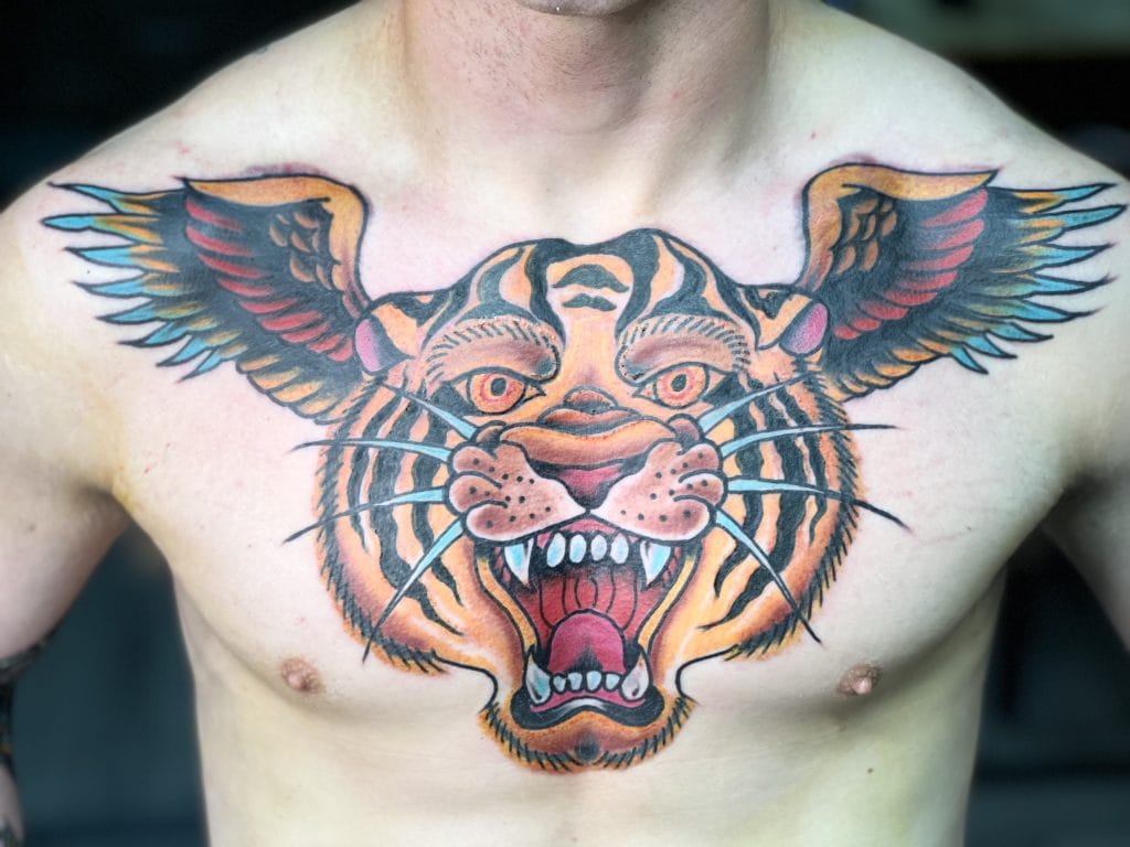 Colorful tiger face tattoo with wings extending from the head across the chest.