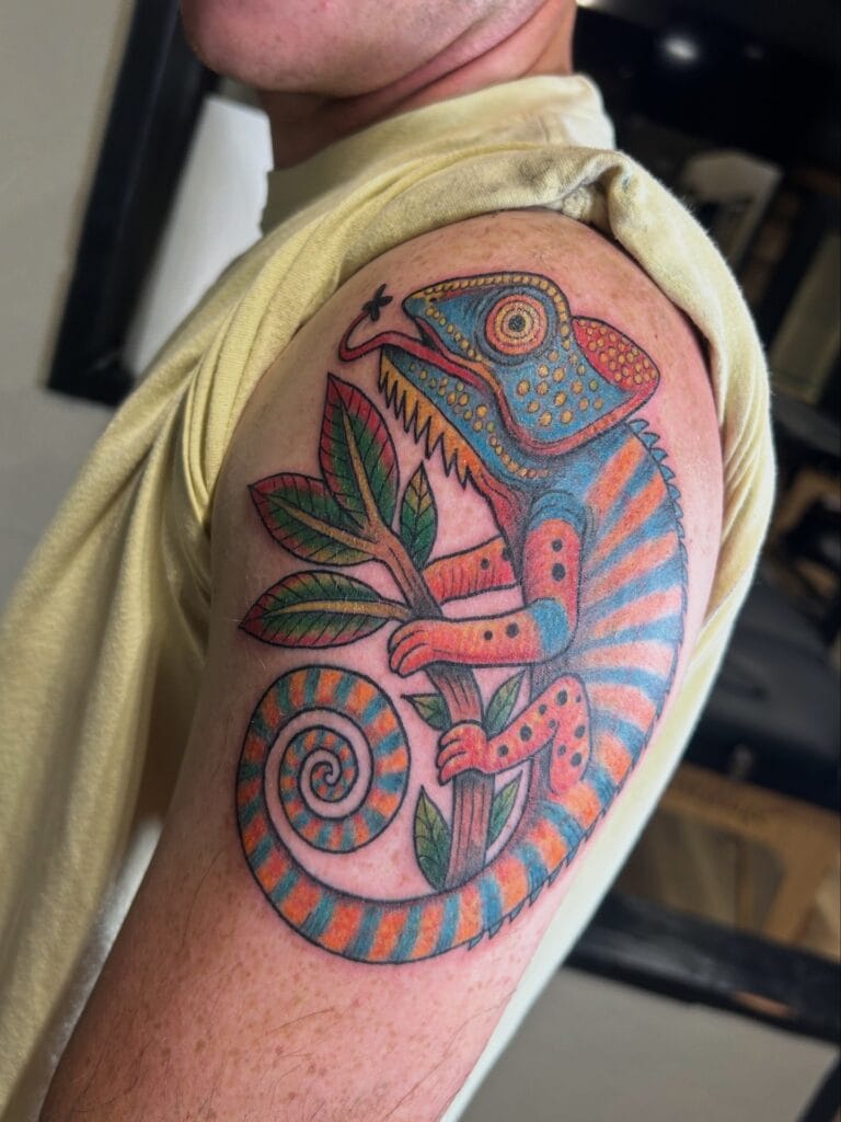 Colorful chameleon with a spiral tail, perched on a branch with green leaves.